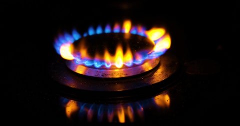 Blue flame of gas stove on black background. Kitchen burner turning on. Natural gas inflammation. chemical reaction. Staining the flame in yellow-red color when sprinkled with salt.