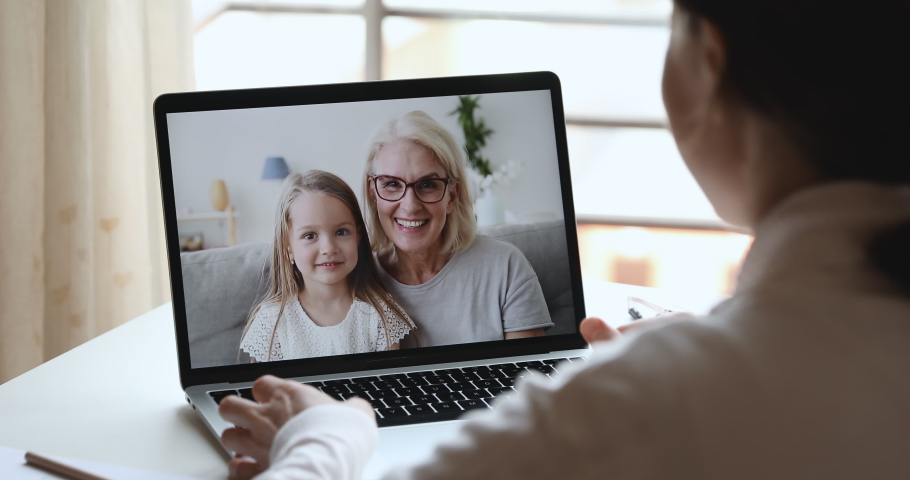 Young woman mom, doctor or tutor video calling chatting by web cam app with happy cute child daughter and old grandma babysitter on laptop screen. Family videocall concept. Over shoulder closeup view Royalty-Free Stock Footage #1050387301