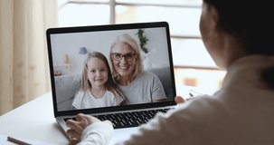 Young woman mom, doctor or tutor video calling chatting by web cam app with happy cute child daughter and old grandma babysitter on laptop screen. Family videocall concept. Over shoulder closeup view
