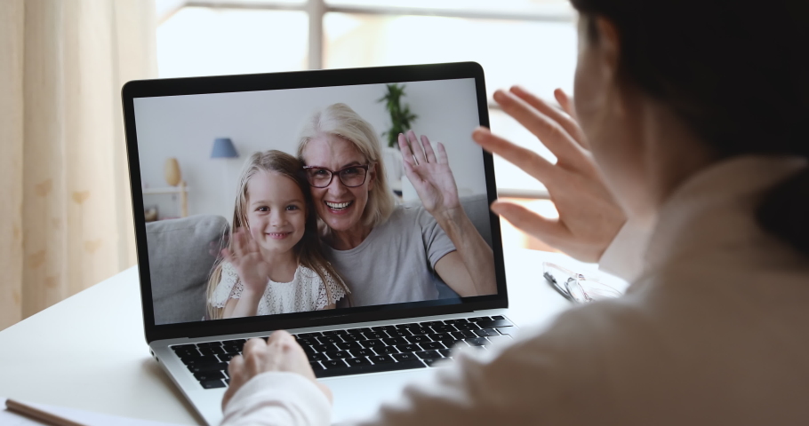 Young woman mom, doctor or tutor video calling chatting by web cam app with happy cute child daughter and old grandma babysitter on laptop screen. Family videocall concept. Over shoulder closeup view | Shutterstock HD Video #1050387301