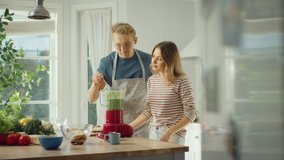 Handsome Young Man in Glasses Wearing Apron and Beautiful Girl are Making A Smoothie in the Kitchen. Happy Couple are Preparing Healthy Organic Beverage and Tasting it from a Spoon. - Powered by Shutterstock - Get 15% off with code: PIKWIZARD15