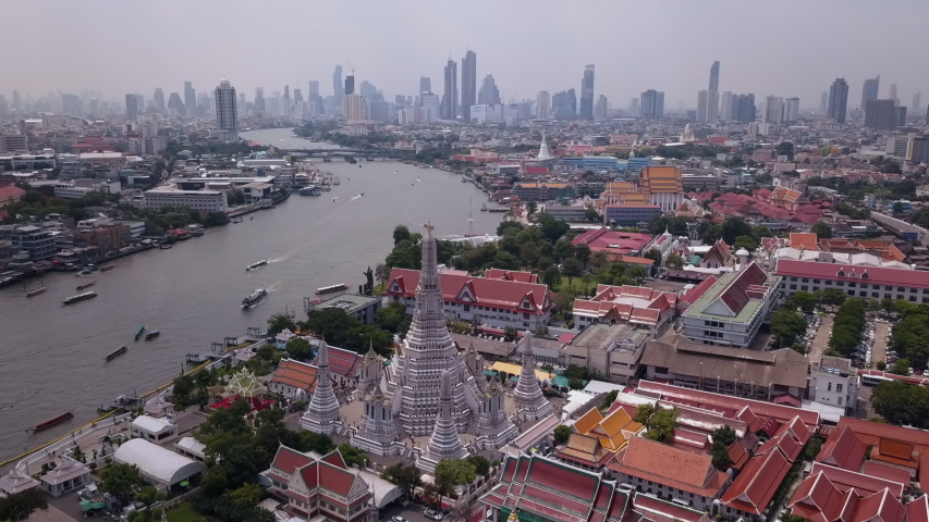 Aerial drone view of Bangkok city in Thailand. Busy water traffic in the main river of Bangkok. Asian city real estate development with heavy traffic and modern skyscrapers in the background.  Royalty-Free Stock Footage #1050390436
