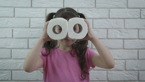 Funny kid with toilet paper. A little girl looks through binoculars from toilet paper.