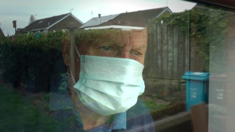 UK lockdown. Coronavirus. Old man wearing face mask, PPE. Looks out of nursing, care home window. Social distancing, self isolation, stay at home, Covid 19. Yorkshire, England UK. 12/04/2020