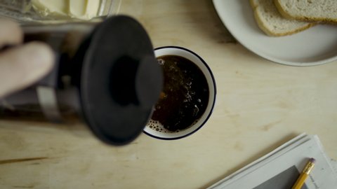 Morning coffee pouring into cup top down view. Closeup of a white cup of coffee and toast. Available in 4K and HD. This tea video clip is suitable for breakfast scenes. Download here.