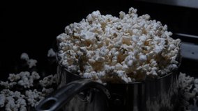 4k, 60 fps clip of a pot overflowing with popcorn while it is still popping.  Camera orbits to the right.