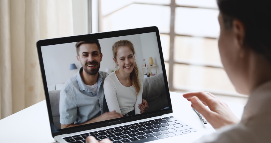 Happy young couple conferencing female friend in webcam chat enjoy virtual communication from home. Millennial people talking using computer video call app on laptop screen. Over shoulder closeup view Royalty-Free Stock Footage #1050420466