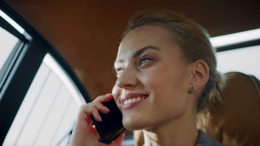 Portrait of joyful businesswoman talking mobile phone at vehicle. Cheerful female professional having phone call at luxury car. Positive business woman calling smartphone at remote workplace