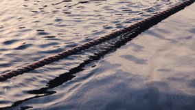 Ripples sea waves as water texture background and anchor rope, sunset scene