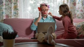 Home quarantine self-isolation. A middle-aged man working remotely from home. His little daughter getting in the way all the time. She tieing bows on his head, painting his lips and putting on makeup - Powered by Shutterstock - Get 15% off with code: PIKWIZARD15