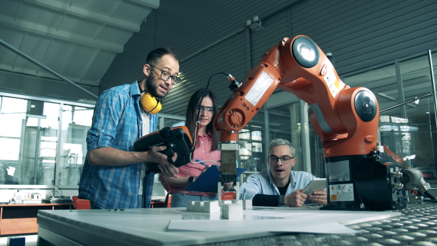 Group of engineers are holding an experiment with a robot. Young electronics engineer studing robotics in high school laboratory.