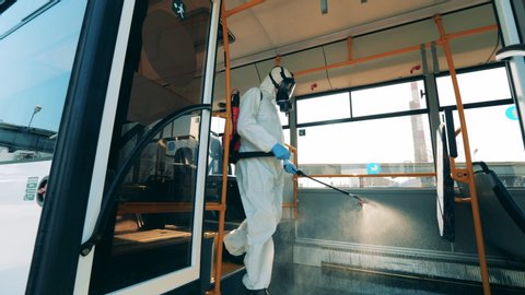 Interior of a bus is being chemically disinfected by an inspector. Coronavirus prevention, epidemic concept.