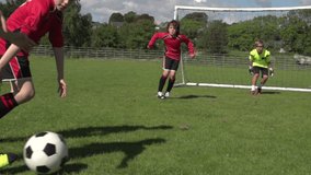 Boys / Children playing soccer / football outdoors on a sunny day. One child kicking the ball past the young goalkeeper and scoring a goal. Slow motion. Stock Video Clip Footage