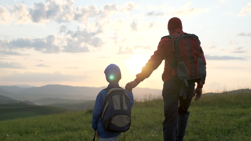 Happy family outdoors trip. Father and son traveling. Little boy child hiker tourist traveler backpacks walking on sunset mountain, hiking vacation travel tourism adventure summer nature. 4 K slow-mo Royalty-Free Stock Footage #1050448558
