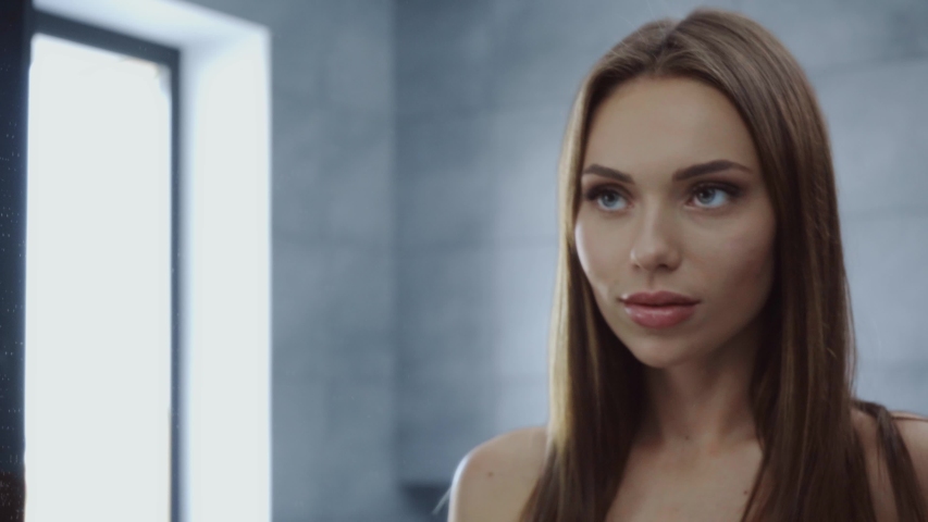 beautiful young woman plucking eyebrows with tweezers in bathroom