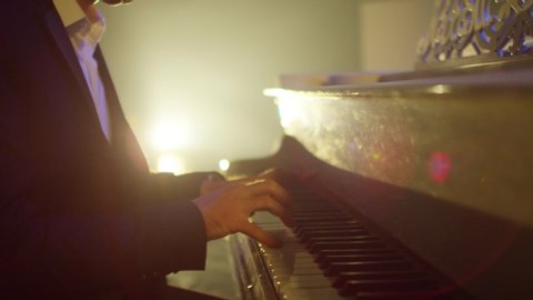 Footage of male hands playing grand piano . Man touches fingers on keys . Pianist plays in beautiful grand piano on stage in concert . Close up . Shot on ARRI ALEXA movie camera in slow motion .
