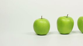 Stand out from the crowd - A line of green apples and then a Red apple -Tracking shot on White Background. Stock Video Clip Footage