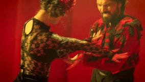 Beautiful couple dancing latin dance . Professional dancers dancing flamenco, rumba or salsa on red background. Pair in spanish dress performs dance movement. Shot ARRI ALEXA Cinema Camera .
