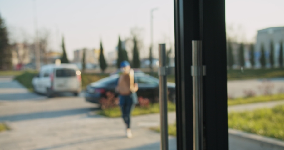 Back view on male pensioner coming out from building and taking grocery deliveryfrom young Caucasian female courier. Woman in mask and gloves handing packet with food to old man. Pandemic concept. Royalty-Free Stock Footage #1050466048