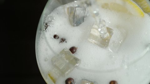 Fizzy tonic splashing over ice cubes in a fresh gin cocktail drink | Summer party | close up