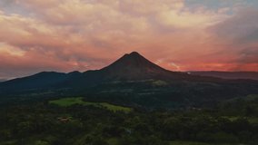 Seamless Video Loop - Cinemagraph time-lapse of the impressive Arenal Volcano at La Fortuna, Costa Rica by sunset. Red and orange clouds are moving towards the crater peak.