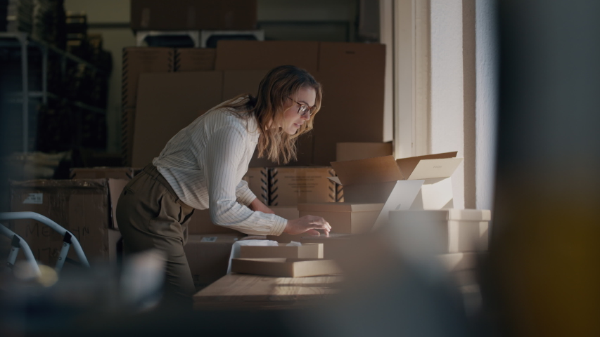 Woman checking a laptop for new order and packing the product for delivering to the customer. Online business owner working at the office, preparing the order
 Royalty-Free Stock Footage #1050470638
