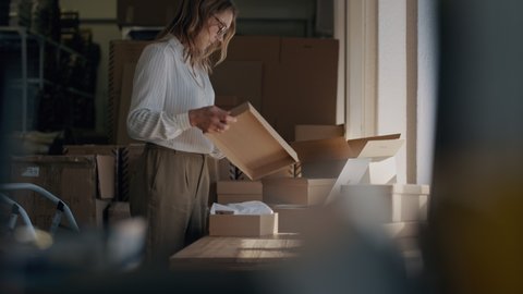 Woman checking a laptop for new order and packing the product for delivering to the customer. Online business owner working at the office, preparing the order

