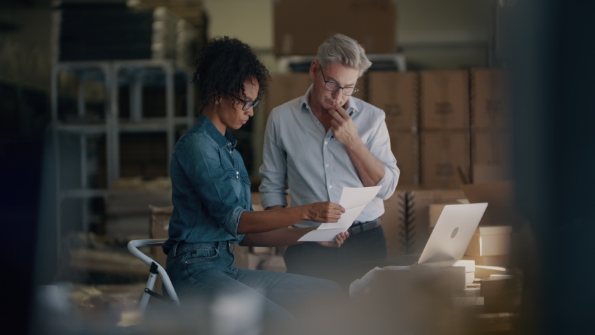 Business partners working together at the warehouse of an online store. Two business people working in dropshipping office reading and verifying the invoice before shipping the product to the customer Royalty-Free Stock Footage #1050470641