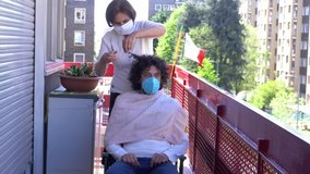 Europe, Italy, Milan - Pandemic emergency n-cov19 Coronavirus - Domestic life in quarantine of 70 year Italian old lady  with  mask CUT  HAIR ON THE BALCONY OF  HOME TO SON/ GRANDDAUGHTER