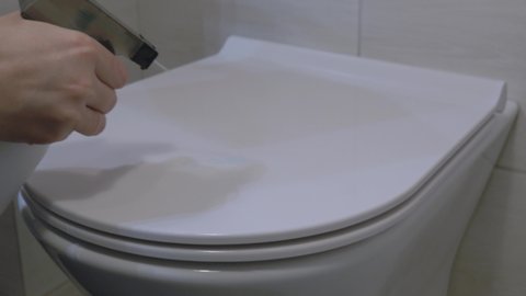 Housewife washes a toilet, toilet disinfection, leaning toilet, hands wipe the toilet, close up.