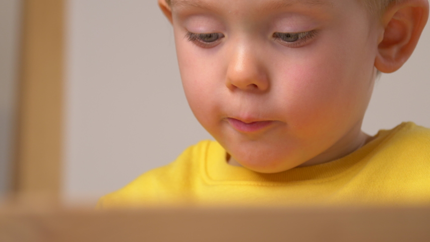 Child is playing indoor, diligently doing something. Close up of kid