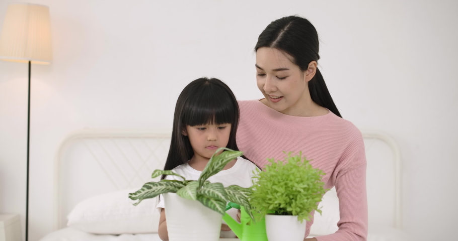 Young asian mother teaching her little daughter to planting trees in bedroom.
