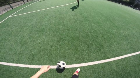 POV of female soccer player dribbling a ball on green field and then scoring a goal while training outdoors on sunny day