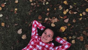 A beautiful woman lies on autumn leaves in the forest. The video was taken on a drone. The view from the top.
