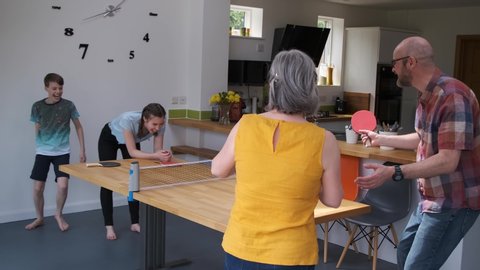 Family Playing Table Tennis Game On Kitchen Table Because Of COVID-19, Coronavirus Pandemic Lockdown, UK