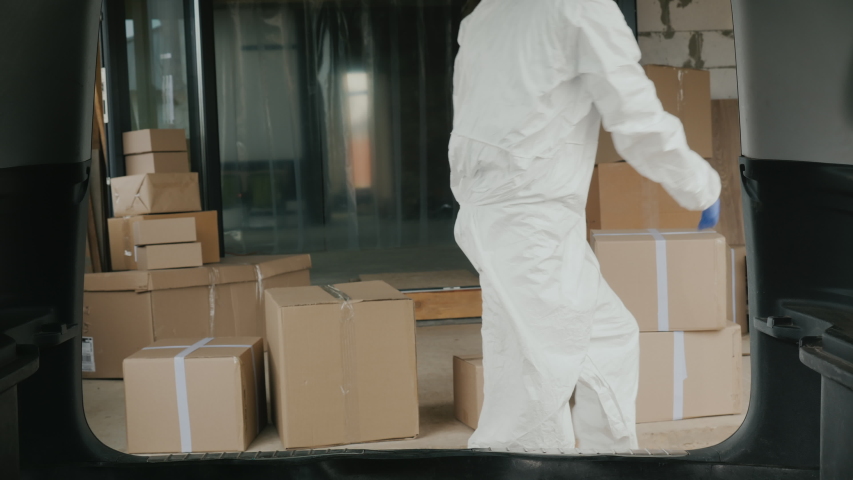 Worker in protective clothing loads boxes of medicines into the trunk of the car Royalty-Free Stock Footage #1050519952