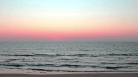 Slow motion video of Calming ocean wave with pink & purple sunset horizontal on beautiful twilight colorful pastel sky background in tropical summer or spring sunlight & sun ray at Andaman sea island 