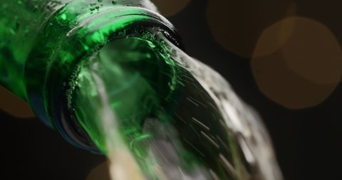 Stream of beer runs through the open green glass bottle in macro slow motion video, cold beer pours out, liquid flows, beverage tabletop, alcohol drink, 4k 120p Prores HQ 10 bit