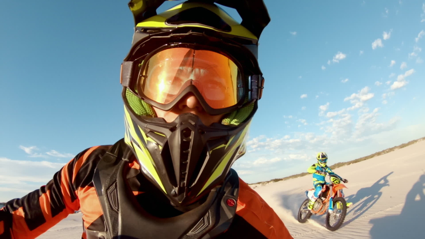 Shot from helmet mounted action camera of professional dirt bikers practising in desert. Motorcylists doing off roading on sand dunes.
 Royalty-Free Stock Footage #1050529093