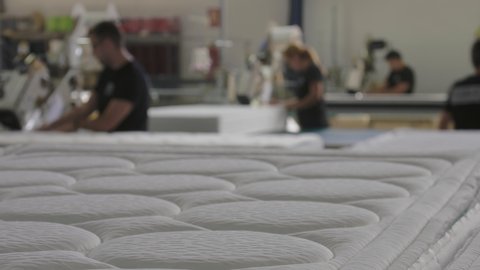 Mattress finished at the end of the production line of a mattress factory with workers working.