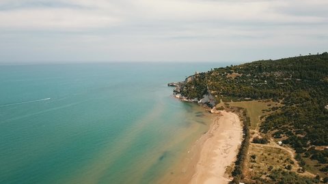 Aerial: Tracking shot of mediterranean coastline with sandy beach and forest during summer near Gargano, Italy