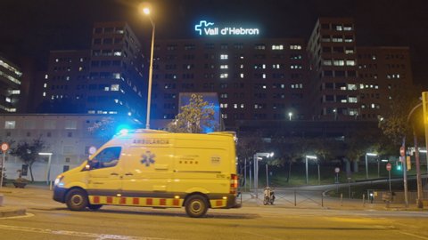 4K Ambulance driver in hospital area at night, emergency amid coronavirus pandemic crisis in Barcelona, Spain, March 2020