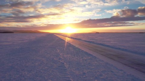 Aerial sunset over frozen lake with track for ice driving, Arjeplog, Lapland, Sweden