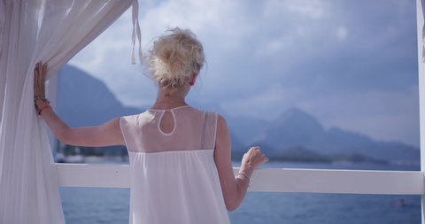 Kemer, Turkey - August 30, 2019: Female on vacation opening white curtains and looking at Mediterranean sea.: dziennikarski film stockowy