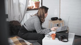 Young, beautiful woman working in front of a computer at home. Nice girl conducts home lessons online. Conducting a business video call from home. Online lectures for the isolated.