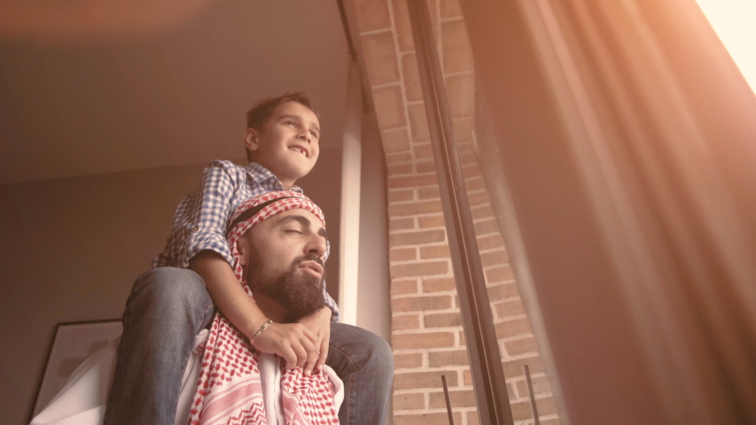 Arabic son and his and her father looking through the window. Isolation at home for self quarantine. Concept home quarantine, prevention COVID-19. Coronavirus outbreak situation Royalty-Free Stock Footage #1050551776