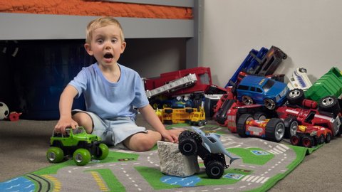 Little boy is playing with toy truck car in his room alone. Child playing with toys (cars, trucks) indoor. Activities for kids at home