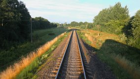Back view of railroad and a beautiful green nature from a train passing on countryside land. Railroad travel or railway tourism concept. Slow motion back view 4K video.