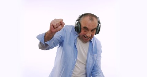 The old man in headphones, listening to music, dancing, smiling, cheerful. A very funky elderly grandpa dj.