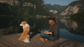 Awesome shot of hipster woman or millennial freelancer write blog post or work on lake laptopwith dog. Working remotely